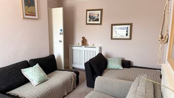 A living room with two sofas, a radiator, and framed pictures on the wall.