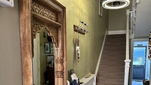 A hallway with a large ornate mirror, a white console table, and a staircase.