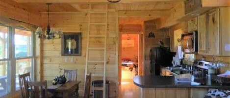 Interno di una baita in legno con zona pranzo, angolo cottura e camera soppalco.