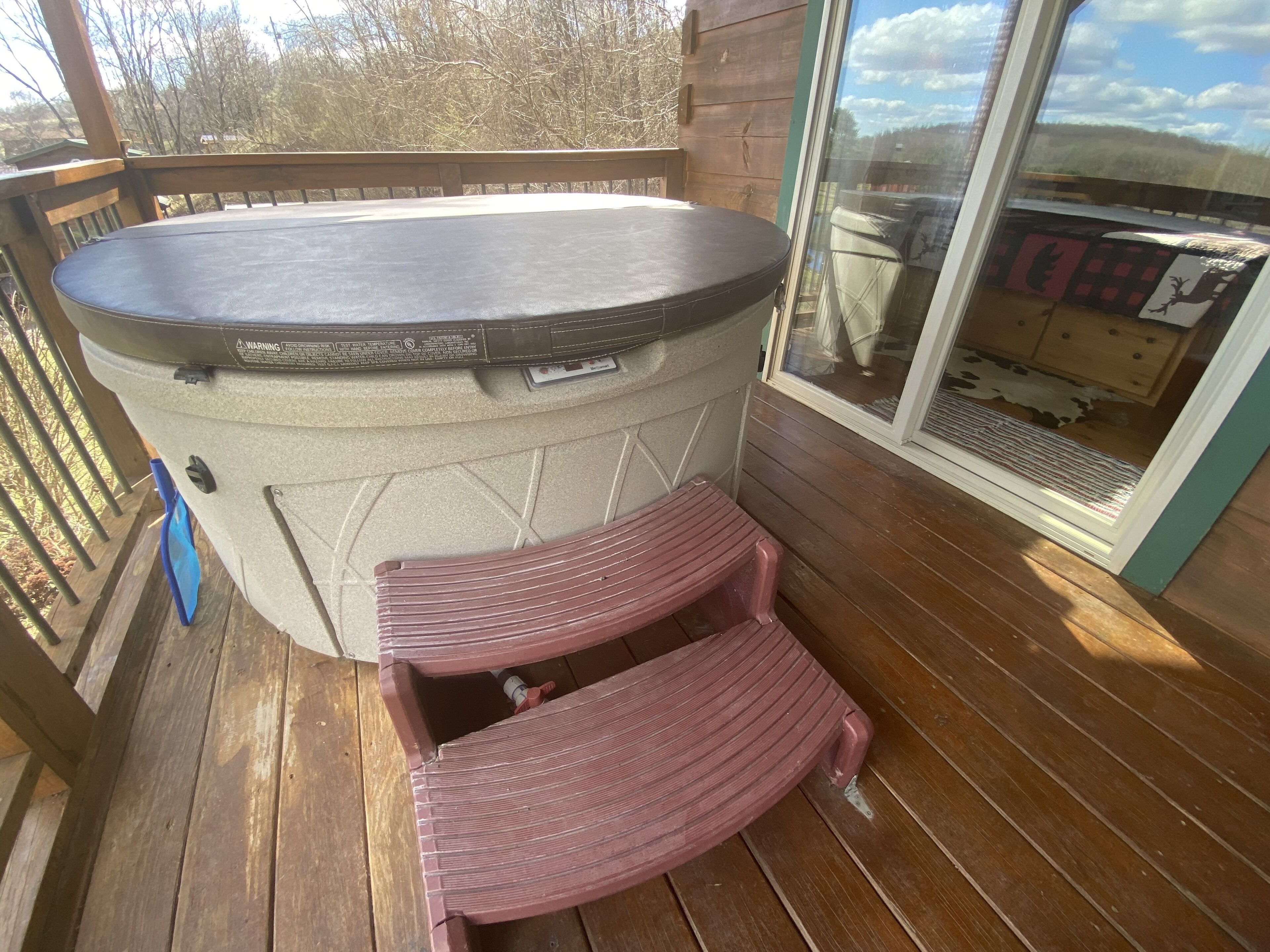 Ein Whirlpool auf einer Holzterrasse mit einer Glastür zum Außenbereich.