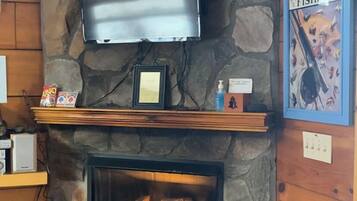 A stone fireplace with a TV mounted above it, a framed picture on the mantel, and a sign for hunting and fishing.