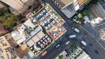 An aerial view of a hotel with multiple floors, a rooftop garden, and a parking area.