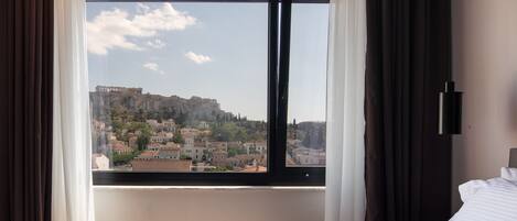 A hotel room with a large window offering a view of a historic cityscape.