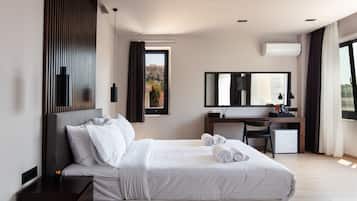 A modern hotel room with a large bed, a desk, and a view of the outdoors.