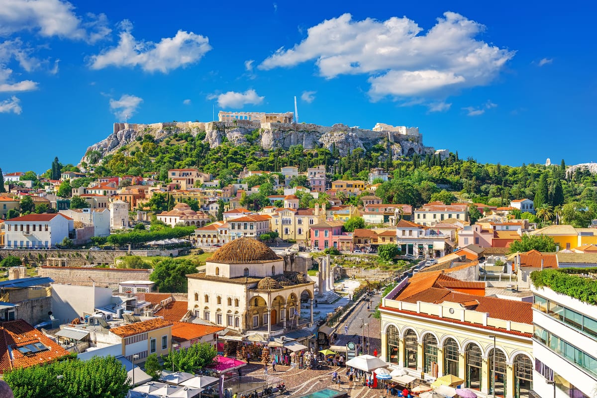 A historic town with a prominent castle on a hill, traditional buildings, and a central square with shops and cafes.
