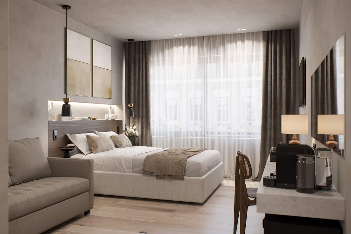 A modern hotel room with a bed, a sofa, a desk with a lamp, and a large window with curtains.