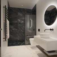 Un bagno moderno con una parete in marmo nero, un lavabo bianco e uno specchio grande.