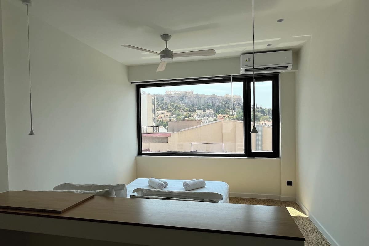 A hotel room with a large window offering a view of a cityscape and a historical site.