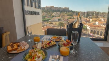 Un tavolo imbandito con prodotti per la colazione, una bottiglia di champagne e vista su un centro storico.