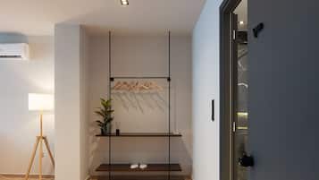 A modern room with a wooden floor, a standing lamp, a plant, a shoe rack, and a door with a camera.