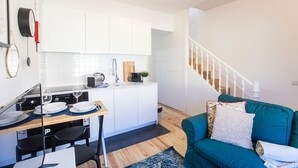 A modern kitchen with white cabinets, a dining table set with plates and glasses, and a staircase leading to another level.