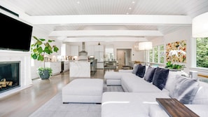 A spacious living room with a large sofa, a fireplace, and a TV. - Newly constructed contemporary home, gunite heated pool, hot tub, deck with... (East Hampton)