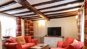 A cozy living room with a wooden ceiling, a television on a cabinet, and a red sofa set.