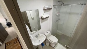 A bathroom with a sink, toilet, mirror, and glass shower enclosure.