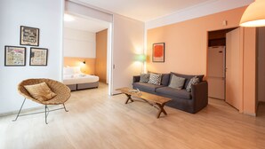 A modern living room with a sofa, a wicker chair, a coffee table, and a door leading to a bedroom. - Elegant Retreat in Kolonaki - Renovated April 2026 (Athens)
