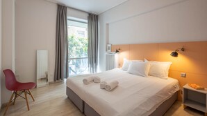A hotel room with a bed, a chair, a nightstand, and a window with curtains. - Elegant Retreat in Kolonaki - Renovated April 2026 (Athens)