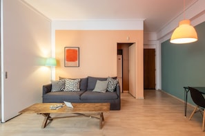Un salon comprenant un canapé, une table basse, une lampe et un luminaire suspendu.