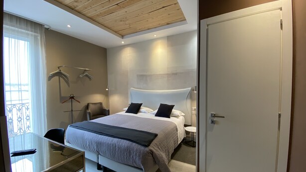 A modern bedroom with a large bed, bedside tables, a desk, and a wardrobe. - Residenze Romano Albergo diffuso & spa (Foggia)