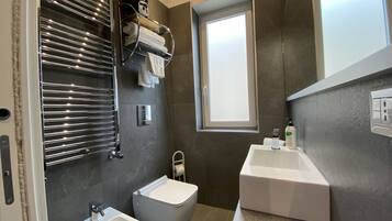 Un bagno moderno con asciugamano integrato, un bidet, un lavandino e uno specchio.