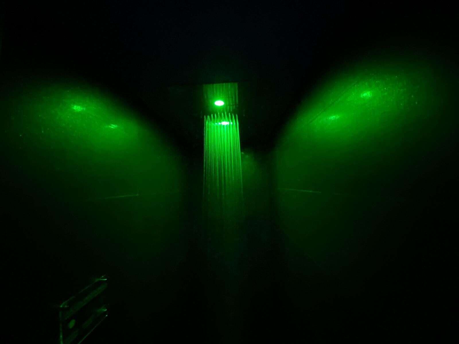 A dark corridor with green lighting and a central vertical structure.