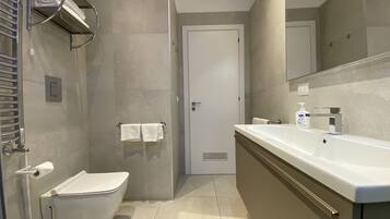 Une salle de bain moderne équipée de toilettes, d’un bidet et d’un lavabo.