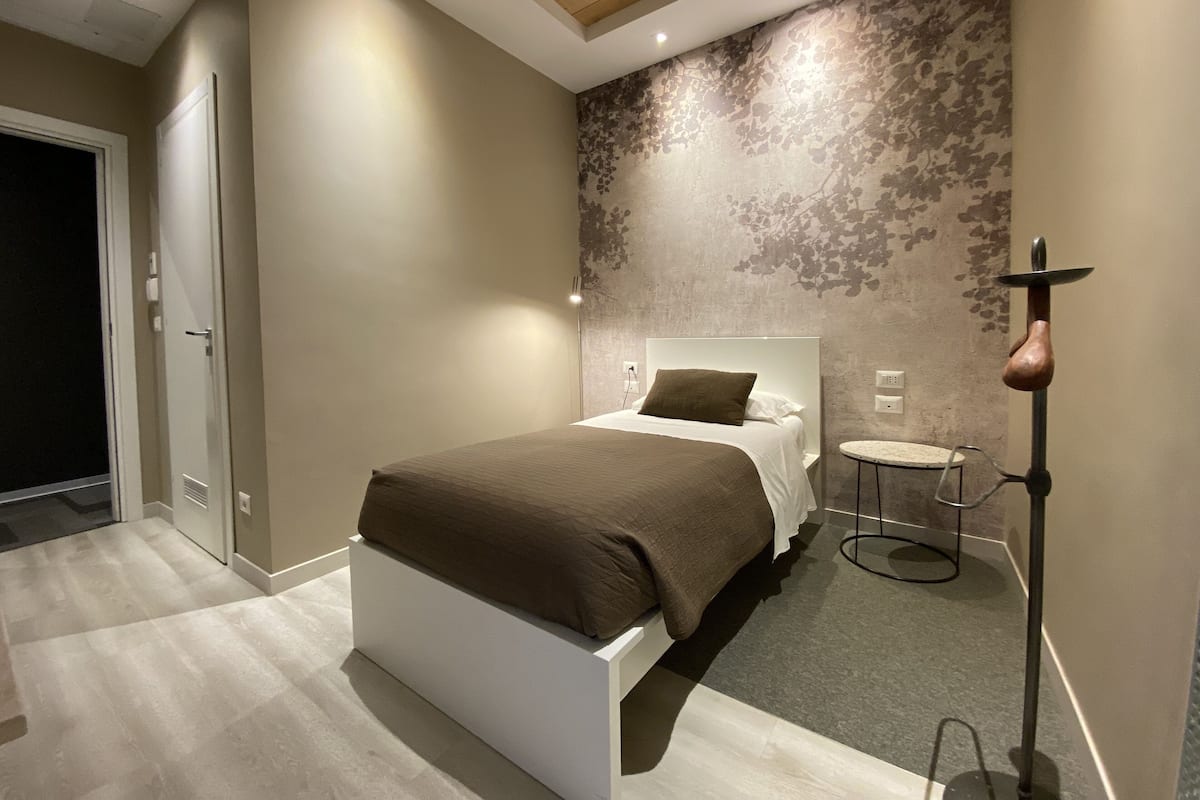 A modern bedroom with a large bed, a small round table, and a unique wall-mounted lamp.