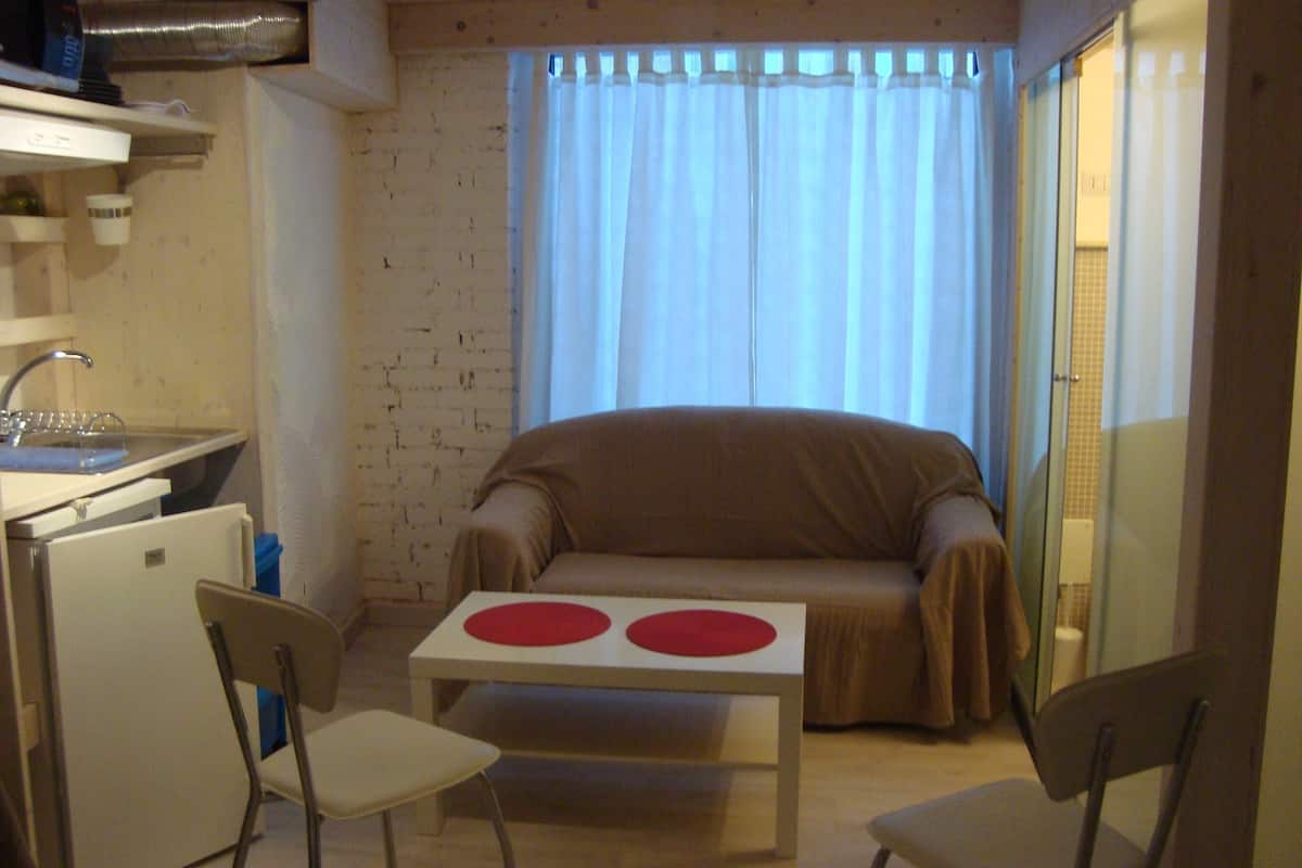 A compact living space with a kitchenette, a sofa, a small table, and two chairs.