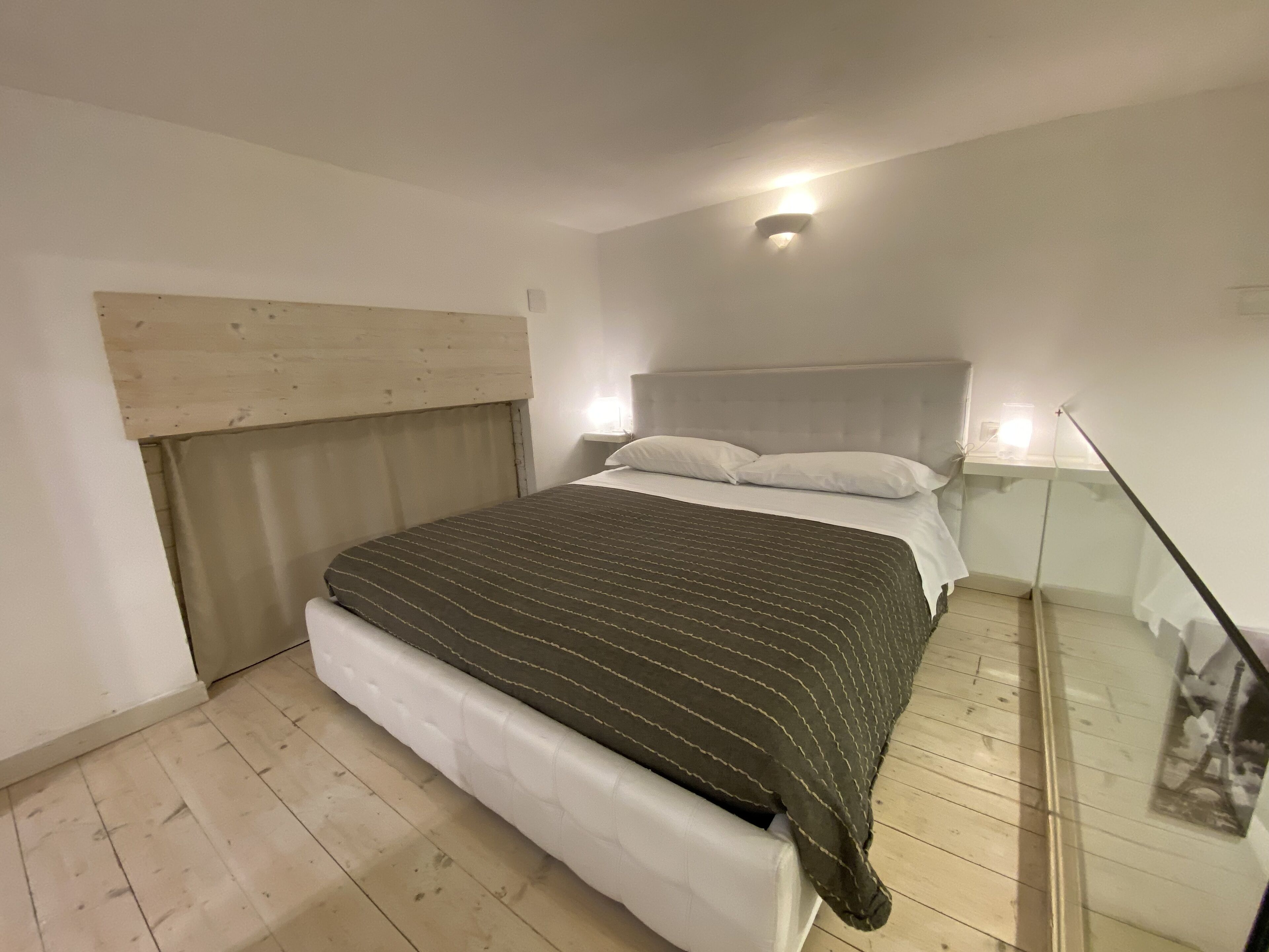 A bedroom with a bed, a headboard, a bedside table, and a nightstand.