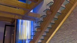 A wooden staircase with glass railings and a brick wall. - Residenze Romano Albergo diffuso & spa (Foggia)