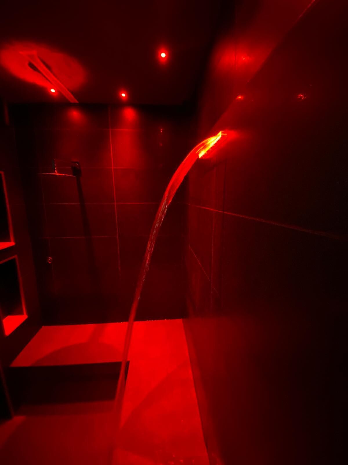 A red-lit shower area with a curved showerhead.