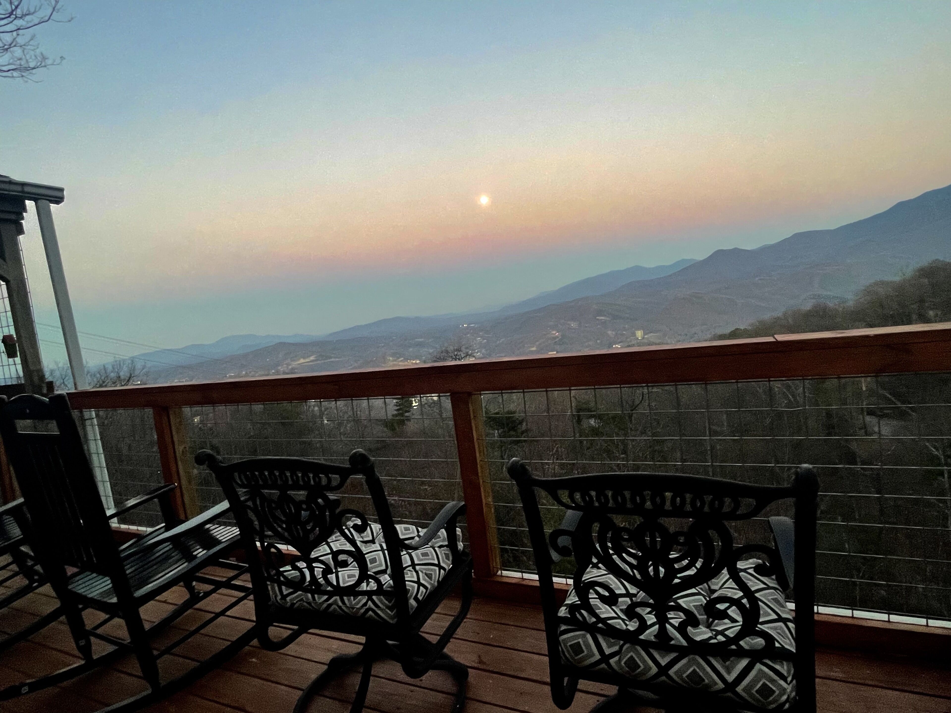 A balcony with two ornate chairs and a view of distant mountains under a clear sky.