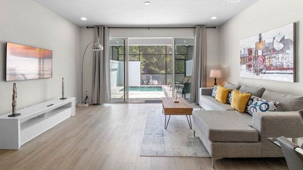 A modern living room with a sofa, coffee table, and artwork on the walls. - Amazing NEW pool house near Disney (Clermont)