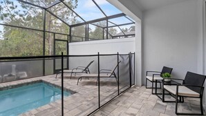 An indoor pool area with a glass ceiling, two lounge chairs, and a table with a potted plant. - Amazing NEW pool house near Disney (Clermont)