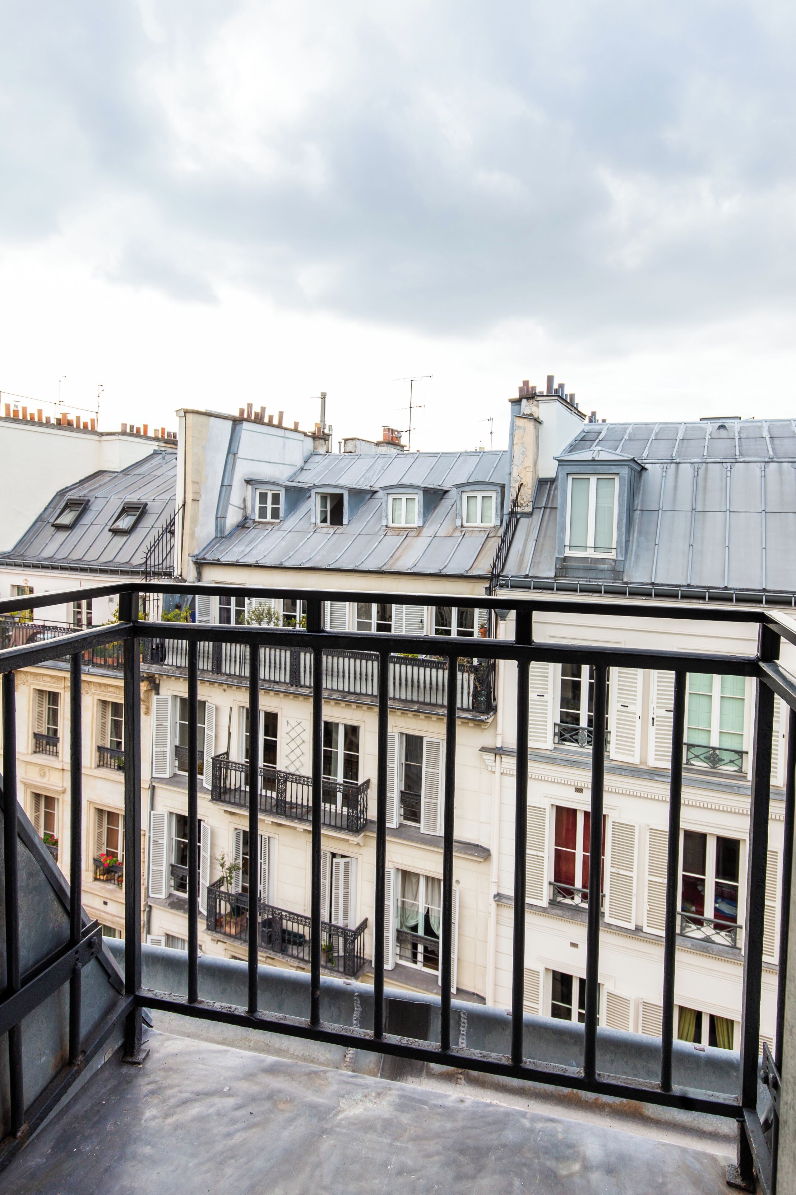 A balcony with a metal railing overlooking a row of buildings with multiple stories and balconies.