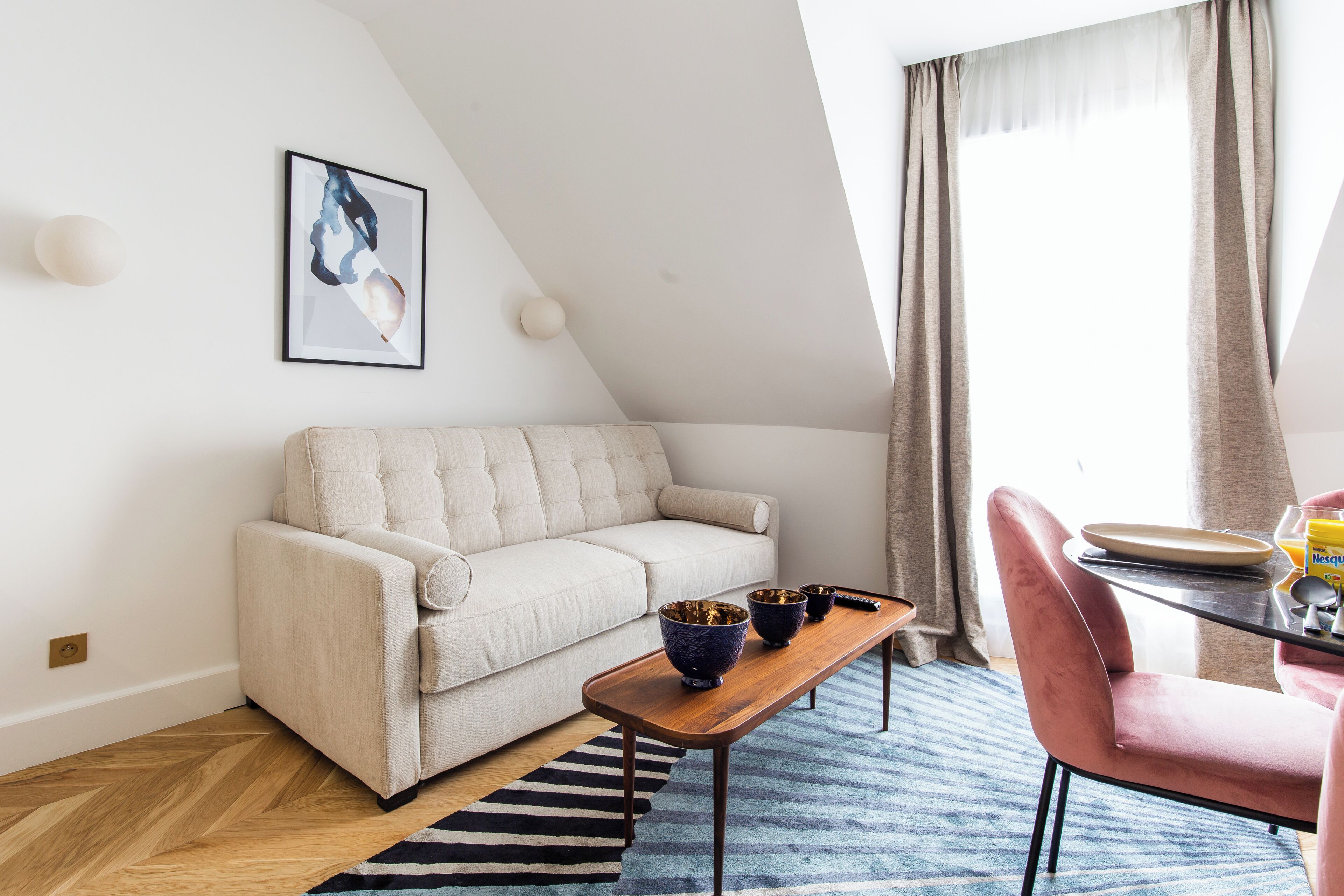 A modern living room with a sofa, a wooden coffee table, and a dining area with a chair and table.