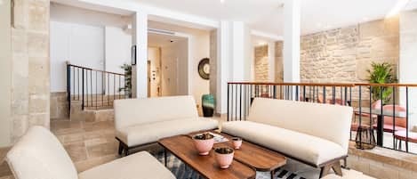 A spacious living area with a high ceiling, stone walls, and a wooden coffee table with decorative items.