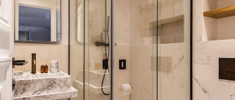A modern bathroom with a glass-enclosed shower, marble countertops, and a white toilet.