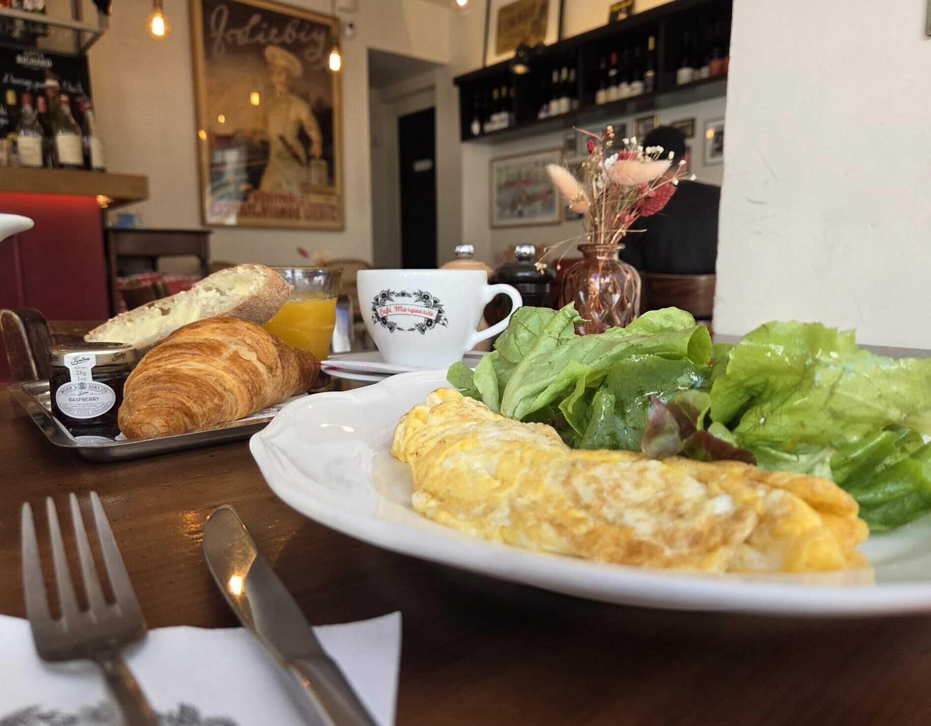 A breakfast setting with croissants, a plate of eggs, and a cup of coffee.