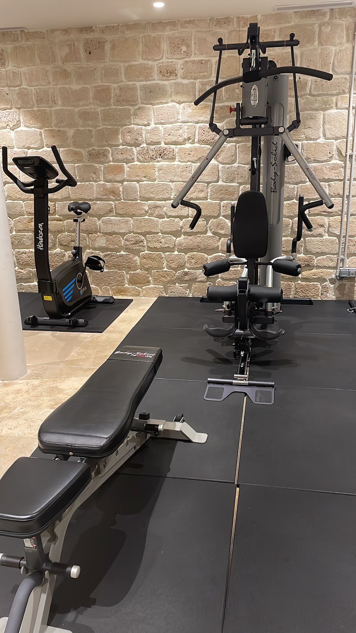 A gym with a stationary bike, a bench, and a weight machine.