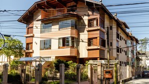 A multi-story residential building with a sloped roof, large windows, and a gated entrance. - LOCAR-IN GRAMADO- Leonardo da Vinci (Gramado)