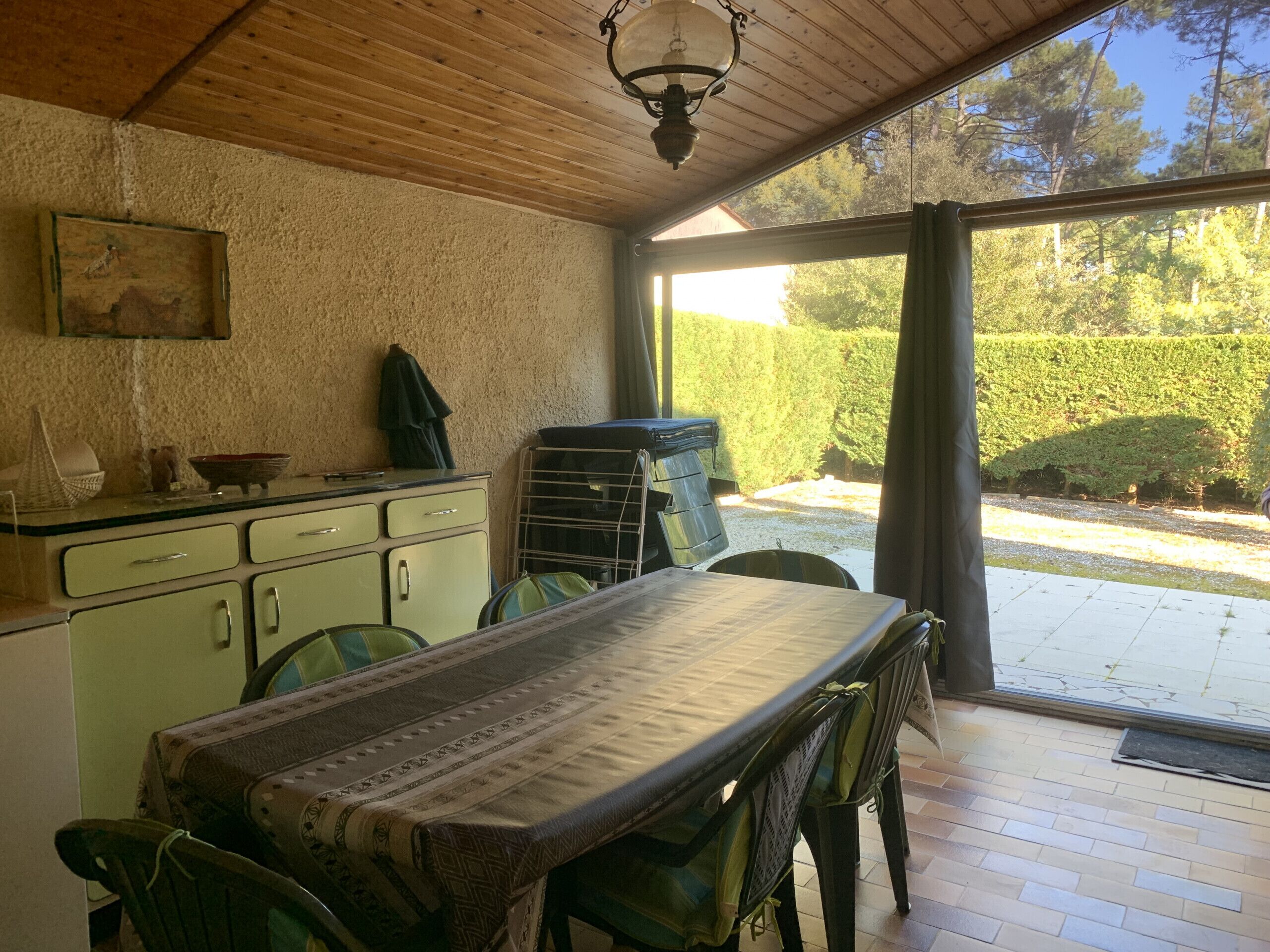 A dining area with a table and chairs, a kitchen with vintage cabinets, and a view of the outdoors.