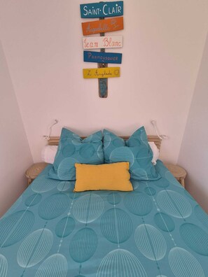 A bedroom with a bed, pillows, and a wall-mounted sign with names.