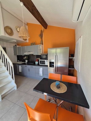 Une cuisine compacte avec un coin repas, comprenant un réfrigérateur, un four à micro-ondes et une petite table à manger avec des chaises.