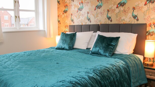 A bed with teal bedding, a grey headboard, and two bedside lamps. - Pippin's Place (Shrewsbury)