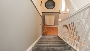 A staircase with a white railing, carpeted steps, and a radiator on the wall. - Pippin's Place (Shrewsbury)
