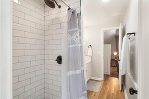 Een bad/douchecombinatie, een haardroger, handdoeken