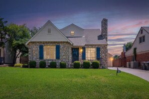 A two-story house with stone facade, blue shutters, and a stone chimney. - EXPO's Cheerful 4-Bed w/Firepit Cherry St, UticaSq (Tulsa)