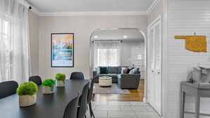 A modern living room with a dining area, a sofa set, and a cityscape painting.