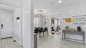 A modern kitchen with a dining area, white walls, and a light wood floor.