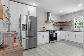A modern kitchen with white cabinets, stainless steel appliances, and a patterned backsplash.